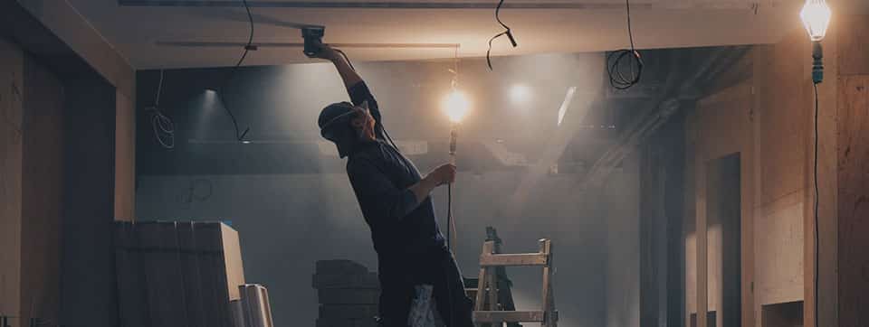 worker putting up drywall inside of a house